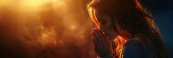 Woman prays to god on dark studio background. Cinematic effect