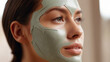 Gorgeous young woman with skin care green mask on her face, for purifying the skin and tightening the pores. Treats oily skin conditions and removes blackheads.