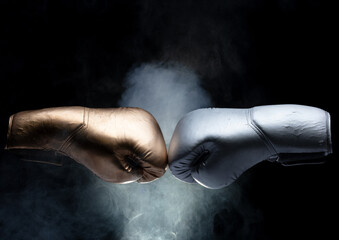 Silver Boxing two glove hit powder together and explode. Gold Boxer glove impact smoke splash as exercise training. Black background isolated