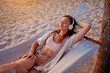 © Goffkein - Young blissful calm woman wearing wireless headphones with closed eyes lie in a hammock and enjoy relaxing music