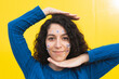 © VISTA by Westend61 - Smiling woman posing with stickers on face against yellow background