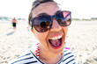 Joyful woman sticking out tongue on sunny beach day