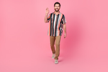 Poster - Full length photo of young man waving hand striped shirt and brown pants trendy look 2024 new collection isolated on pink color background