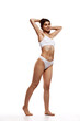 © master1305 - Full-length image of beautiful young girl with tanned, slim, fit body posing in underwear against white studio background. Concept of body and health care, sport, female beauty, wellness