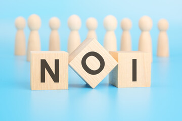 Sticker - forming a conceptual word with cubes in the foreground - NOI - Net Operating Income. the cubes are located on a blue surface in front of wooden figures symbolizing people