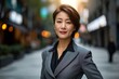 Portait of elegant middle age Asian business woman professional corporate office worker, manager, successful entrepreneur, wearing gray suit standing in city, Generative AI