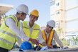 © wichayada - Civil engineer teams meeting working together wear worker helmets hardhat on construction site in modern city. Foreman industry project manager engineer teamwork. Asian industry professional team