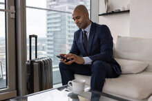 Business executive in travel lounge checking boarding pass on smartphone