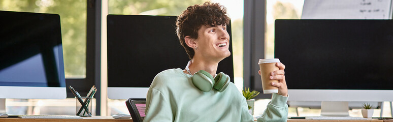 Wall Mural - happy young man with headphones sitting in office chair and holding coffee, post production banner