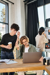 Wall Mural - young businessmen evaluating data on laptop with coworker looking at charts on background, startup