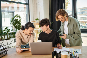 Wall Mural - young team members engaged in project discussion in startup office, men in 20s looking at laptop