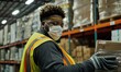 A diligent warehouse worker in a safety vest and face mask diligently scans packages.