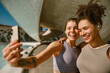 Two smiling female friends making selfie on a smart phone after morning run outdoors