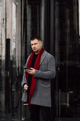 Wall Mural - A handsome man in a gray coat is walking on the street. Businessman talking on the phone