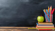 Stack of books with pencils and two apples on the table with school board backdrop. Education or Back to school concept.Back to school background with books and apples over blackboard. 