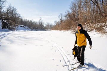 Sticker - Man with backpack in hands walking on skis on snowy river, winter trip, hiking alone, outfit