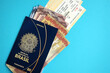 Blue Brazilian passport with money and airline tickets on blue background close up. Tourism and travel concept