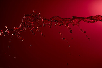 Wall Mural - Red wine splash on a dark red background.