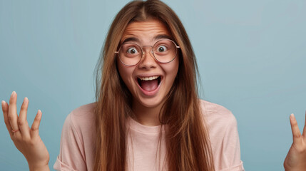 Canvas Print - An ecstatic young woman with glasses is raising her hands in an expressive gesture of overwhelming joy and surprise.