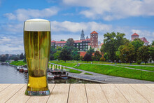 Glass Of Light Beer On Wooden Table In Front Of Wawel Castle In Krakow, Poland