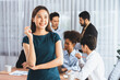 © Summit Art Creations - Young Asian businesswoman poses confidently with diverse coworkers in busy meeting room background. Multicultural team works together for business success. Office lady portrait. Concord