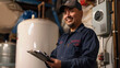 © Studio Nova - smiling man wearing a baseball cap and a blue plaid shirt over a blue work uniform, holding a clipboard in an industrial or maintenance setting, possibly a technician or a worker.