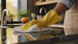 A woman's hand in a yellow protective glove wipes the kitchen counter with a white cloth. Kitchen cleaning concept 