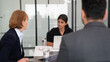© NewSaetiew - businesspeople discussing papers and working on laptops, indicating active discussion or presentation,with a laptop in the background.