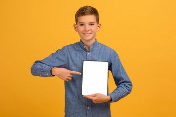 Happy teen male kid pointing at digital tablet with blank white screen