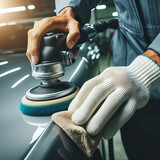 Fototapeta  - Close-up hand male mechanic wearing suit for working in garage for safety in risky work, mechanic standing using polishing machine scrub surface car that comes garage make new color.
