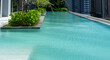 Elegant infinity pool with crystal clear water against a backdrop of city buildings and lush foliage.Infinity Pool Overlooking Urban Landscape.