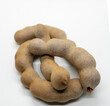 Close-up image of intertwined brown tamarind pods isolated on a white background.