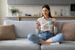 © Prostock-studio - Relaxed woman with coffee and smartphone on couch