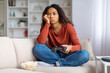 © Prostock-studio - Bored black woman sitting on couch with joystick and looking away