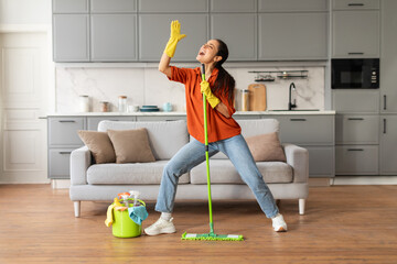 joyful woman dancing with mop in modern living room