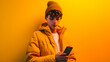 A young content creator guy with smartphone wearing yellow clothes on yellow wall background