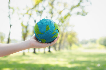 Wall Mural - Young boy's hand holding planet Earth globe at natural park background as Earth day to save this planet with ESG principle and environment friendly energy for brighter future. Gyre