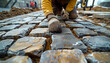 A man laying a pavement of stone cubes.