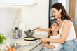© JackF - Girl is naughty while cooking pancakes with her mother. Woman and girl fry pastry dessert in frying pan and have fun, communicate.