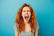 The young emotional angry woman screaming on blue studio background.