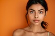 © VolumeThings - Beautiful ethnic naked young woman with healthy skin isolated on orange brown studio background looks satisfied with good skincare routine