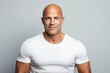 © Inigo - Handsome bald man in white t-shirt on grey background.