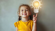 © Nemanja - Closeup of a cute little toddler girl with genius and thoughtful face expression. Female child standing in front of the wall with lightbulb glowing drawing. Thinking of an idea, solve a problem