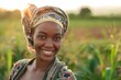 Pretty smiling Black woman in a green field farming concept wearing a headscarf and holding a plastic container