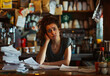 Overburdened Coffee Shop Proprietress Contemplating a Mountain of Paperwork, Weighed Down by Business Woes