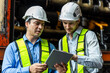 © eakgrungenerd - Railway technician engineer wearing safety uniform and safety helmet holding tablet check work plan standing at site railroad station. Locomotive repairman in factory.
