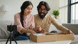 © Yuliia - Couple bloggers customers open package box order online shopping delivery excited happy Arabian man and woman record blog stream on mobile phone at home open parcel win digital tablet unpacking video
