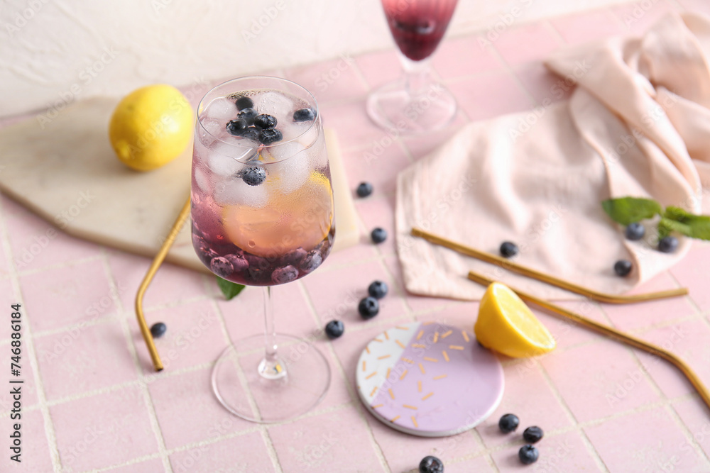 Glass of fresh blueberry lemonade on pink tile table
