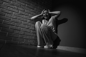 Wall Mural - Scared mature woman sitting in corner