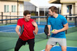 © joescarnici - A young man gives another young man a pickleball lesson